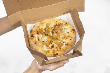 Beyaz arka planı olan karton bir kutuda pizza tutan bir insan eli.