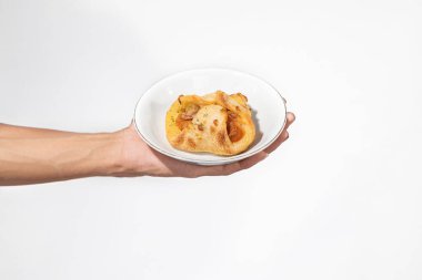 Beyaz arka planı olan bir tabağın üzerinde duran bir insan eli.