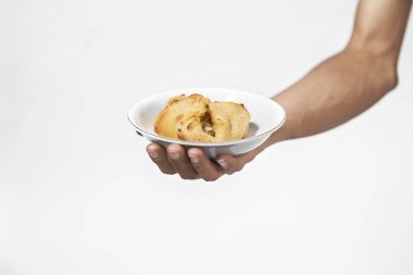 Beyaz arka planı olan bir tabağın üzerinde duran bir insan eli.