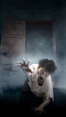 Vücudunda kan ve yaralar olan korkunç bir zombi odanın içinde sürünüyor. Korkunç zombi. Cadılar Bayramı konsepti