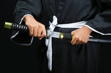 Samuray savaşçısı siyah bir arkaplanla kılıcı tutuyor.