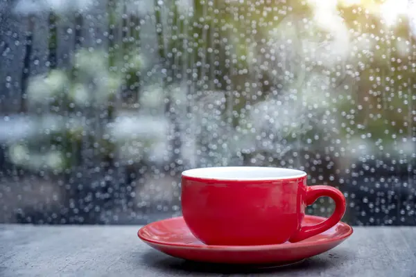 Coffee cup on the table with a clear window and raindrop background