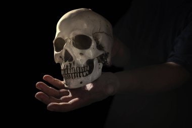 Karanlık bir geçmişi olan insan kafatasını tutan bir el. Korkunç kafatası Cadılar Bayramı konsepti