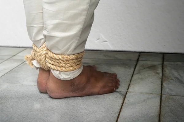 The man's legs are tied by rope. Violence concept