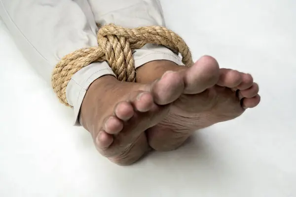 The man\'s legs are tied by rope. Violence concept