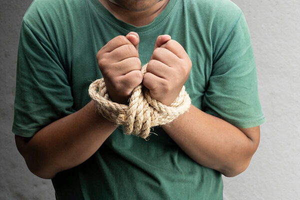 The man's hands are tied by rope. Violence concept