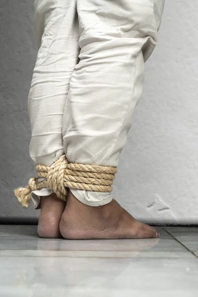 The man's legs are tied by rope. Violence concept