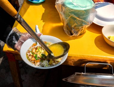 Garson servis için tavuk çorbası (Soto Ayam) hazırlıyor. Geleneksel Endonezya yemekleri