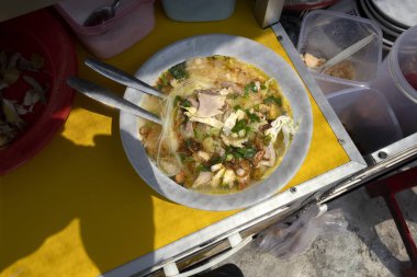 Garson servis için tavuk çorbası (Soto Ayam) hazırlıyor. Geleneksel Endonezya yemekleri