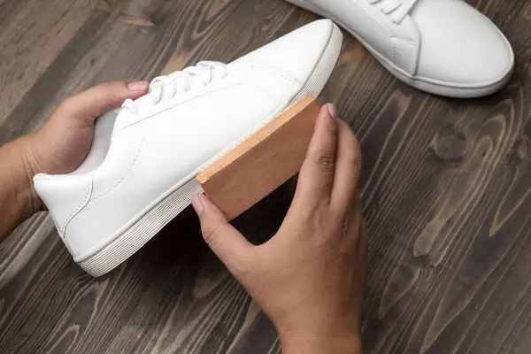 Human hand cleaning white sneakers with a brush. Shoe care concept