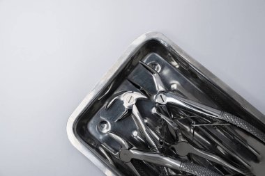 Gri arka plandaki tepside diş aletleri var. Dişçi ekipmanları ve araçları