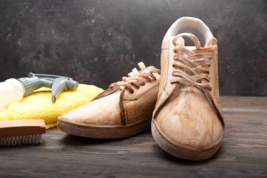 Fırça, mikrofiber bez ve tahta arka planda beyaz spor ayakkabılı şişe spreyi. Ayakkabı bakımı kavramı