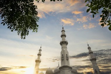 Caminin kubbesi ve minaresi, günbatımı sahnesi arka planında.