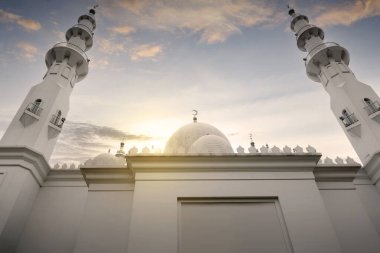 Caminin kubbesi ve minaresi, günbatımı sahnesi arka planında.