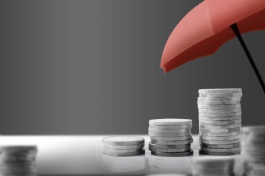 Masada büyüyen gümüş paraların üzerine kırmızı şemsiye. Finansal yatırım kavramı