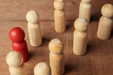 Red wooden figures stand out from the crowd of wooden figures. Leadership concept