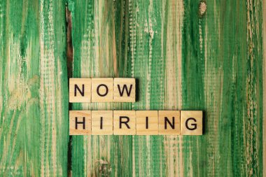 Wooden cubes with Now Hiring letters on a wooden background. Human resources management concept