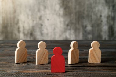 Red wooden figures stand out from the crowd of wooden figures. Leadership concept