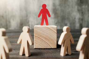 Red wooden figures stand out from the crowd of wooden figures. Leadership concept