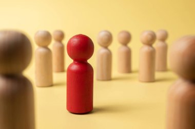 Red wooden figures stand out from the crowd of wooden figures. Leadership concept