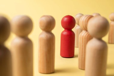 Red wooden figures stand out from the crowd of wooden figures. Leadership concept