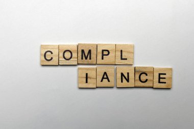 A row of wooden cubes with compliance letters on a white background. Compliance concept