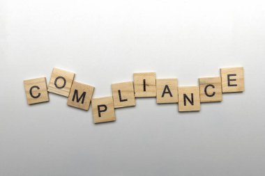 A row of wooden cubes with compliance letters on a white background. Compliance concept