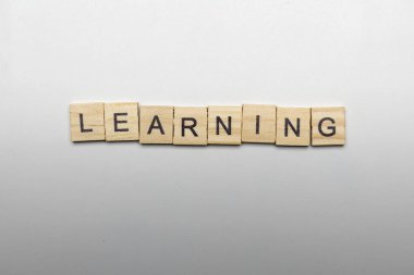 A row of wooden cubes with learning letters on a white background. Learning concept
