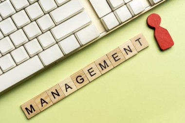 Closeup view of computer keyboard and a row of wooden cubes with MANAGEMENT letters. Management concept