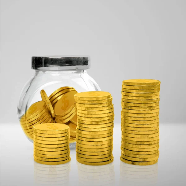 Stairs of golden coins with golden coins in a glass jar on a white table. Financial concept