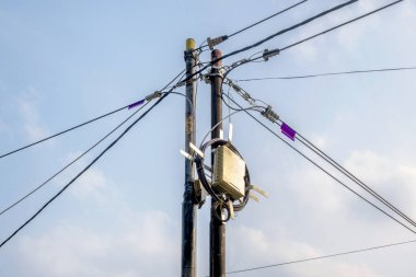 Mavi gökyüzü arka planına sahip yüksek voltajlı elektrik hatları kulesi