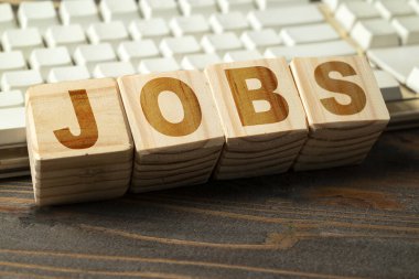 Tahta arka planda bilgisayar klavyeli Jobs yazısıyla ahşap küplerin yakın görüntüsü. İnsan kaynakları yönetim kavramı