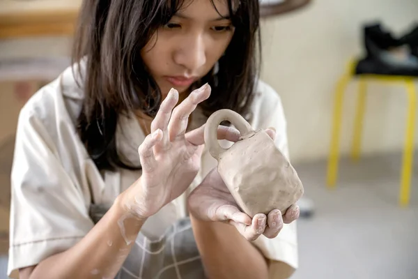 Closeup view of kids making a craft of a porcelain mug from wet clay. Pottery craft clay concept