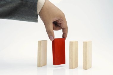 İş adamı, beyaz arka planda izole edilmiş kahverengi tahta bloklara kırmızı bir tahta blok koydu.