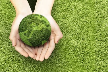 Yeşil çimlerin üzerindeki verimli toprakları gösteren insan eli. Çevre ve iklim değişikliği kavramı