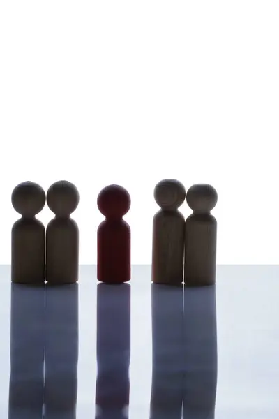 Closeup view of a red wooden figure standing with a row of brown wooden figures on a white background. Human resources management concept