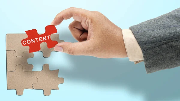 Business hand showing content text on a piece of jigsaw puzzle. Content manager, strategy and creativity concept