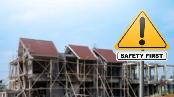 A traffic sign with 'safety first' text with a construction site background. Safety first concept