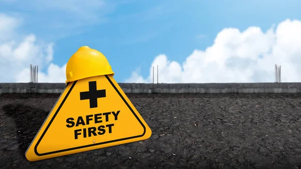 Safety first with yellow sign on asphalt road and yellow helmet as a warning concept of industrial attention for employee awareness. Business concept for Avoid any unnecessary risk live safely and healthcare attention