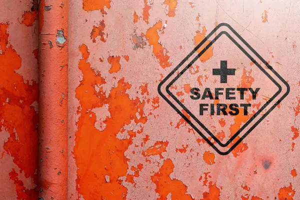Text of safety first sign on grunge red wall background as a warning concept of industrial attention for employee awareness. Business concept for Avoid any unnecessary risk live safely and healthcare attention