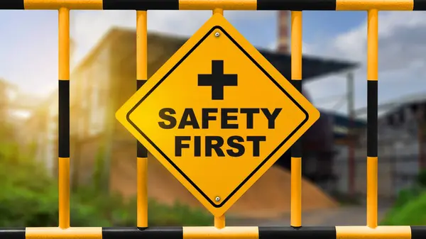 View of safety first with yellow sign hang on yellow fence as a warning concept of industrial attention for employee awareness. Business concept for Avoid any unnecessary risk live safely and healthcare attention