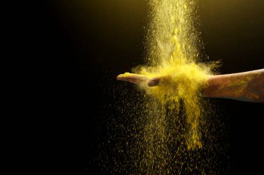 Siyah arka planda renkli Holi tozu olan insan eli. Holi festivali konsepti