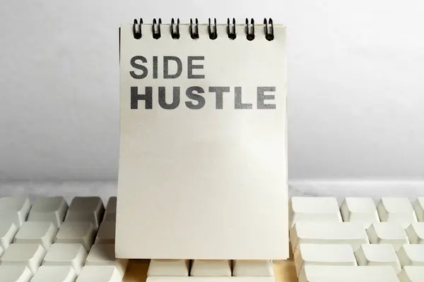 Text of side hustle on blank note book on white keyboard isolated over white background. Side hustle income payment concept. Freelance idea for more job or income.