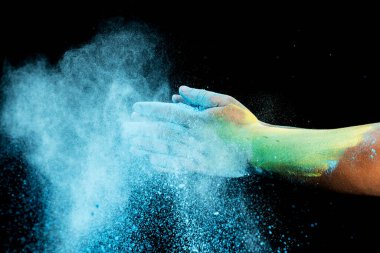 Siyah arka planda renkli Holi tozu olan insan eli. Holi festivali konsepti