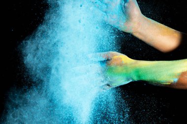 Siyah arka planda renkli Holi tozu olan insan eli. Holi festivali konsepti