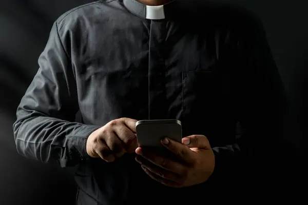 Giovane Sacerdote Possesso Smartphone Toccare Schermo Isolato Sfondo Nero Fotografia Stock