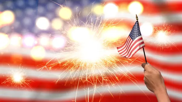 Een Menselijke Hand Die Amerikaanse Vlag Vasthoudt Met Een Vuurwerkachtergrond Rechtenvrije Stockfoto's