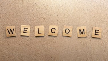 Hoş geldin mesajı ve kumlu plaj geçmişi olan tahta küplerle dolu bir sıra. Giriş konsepti