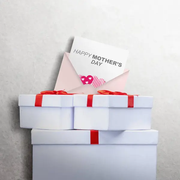 信上有 母亲节快乐 的文字和白色墙壁背景上的礼品盒 母亲节概念 免版税图库图片