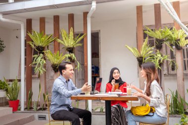 Kafedeki bir toplantıda iş projesini tartışan çok ırklı iş arkadaşlarının portresi